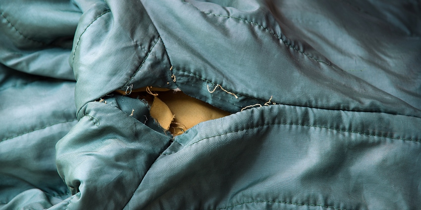 A teal garment is ripped along the seam