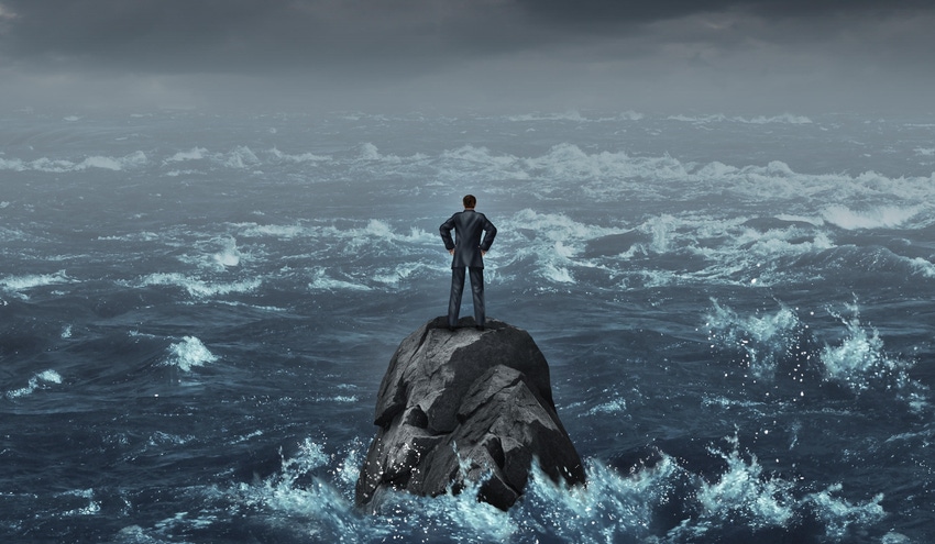 Stranded businessman lost at sea standing on an isolated rock as a business concept for despair or being lost