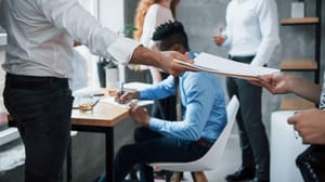 Two people watching as one person passes files to another person. Two people watching as one person passes files to another person.
