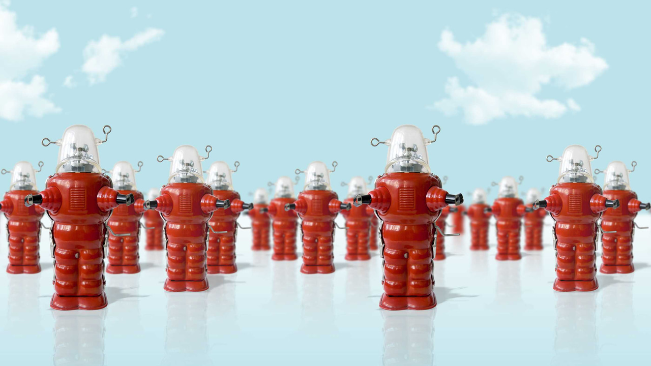 Several rows of toy red robots standing under a cloudy sky. Several rows of toy red robots standing under a cloudy sky.