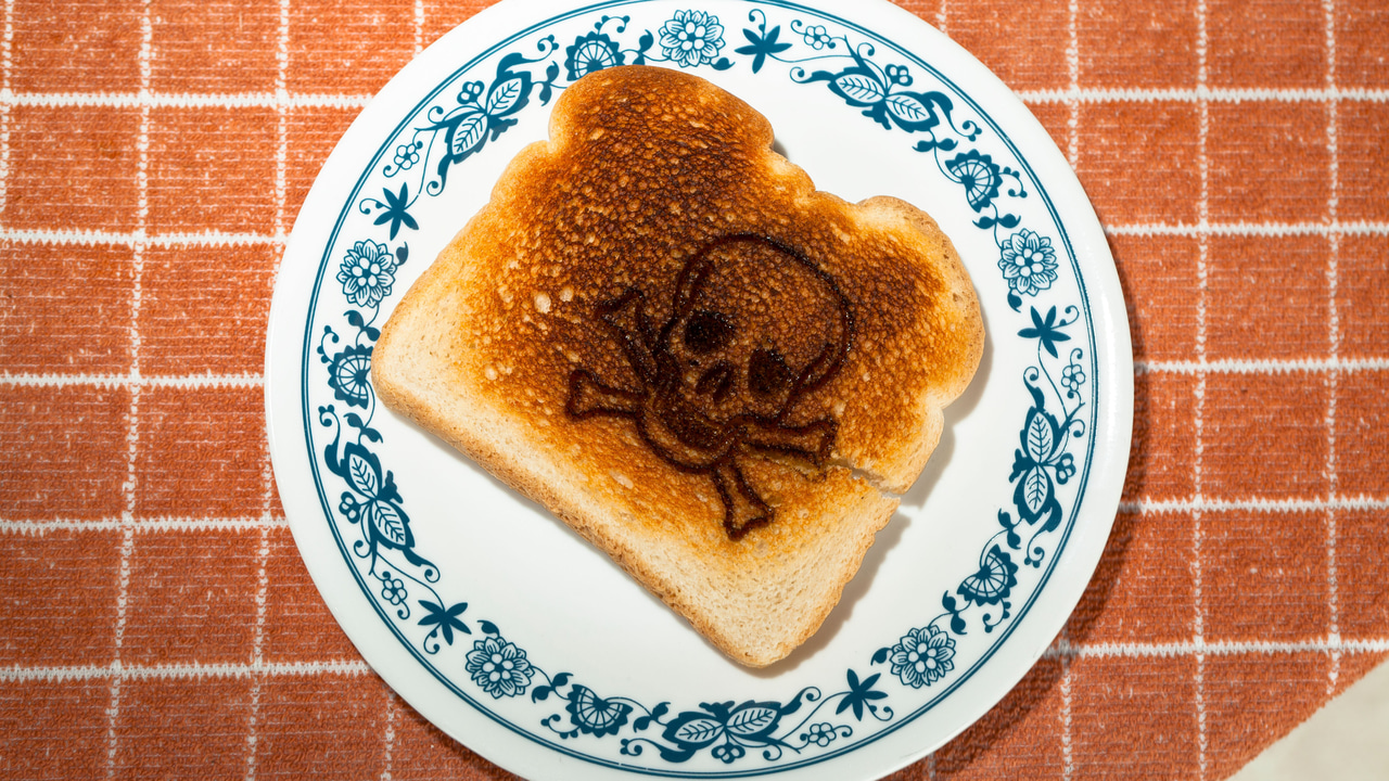 Skull and cross bones burned into a piece of toast on a plate Skull and cross bones burned into a piece of toast on a plate