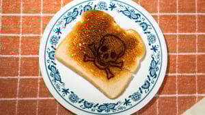Skull and cross bones burned into a piece of toast on a plate Skull and cross bones burned into a piece of toast on a plate
