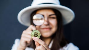 Woman in a white hat holds a magnifying glass and looks at bitcoin