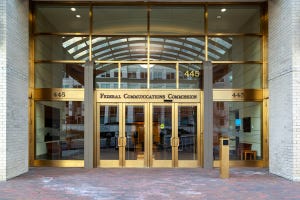 Entrance to Federal Communications Commission office in Washington, DC; glass doors, white brick walls, brass fittings