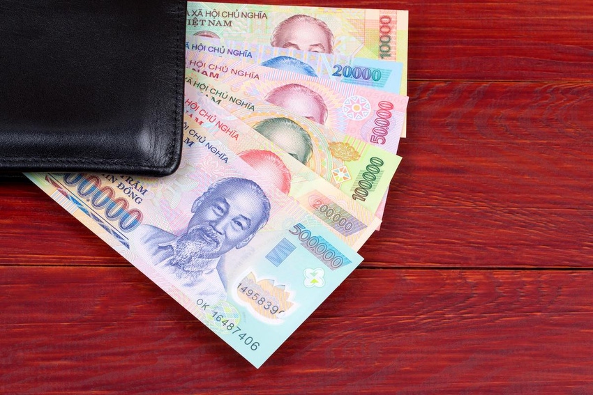 Vietnamese currency splayed under a wallet