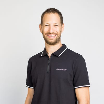 Erez Berkner, co-founder and CEO of Lumigo, smiles in a navy polo shirt. He has blue eyes, light brown hair, and a short beard.