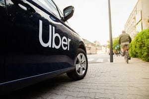 black ride-share car with Uber logo parked halfway on sidewalk