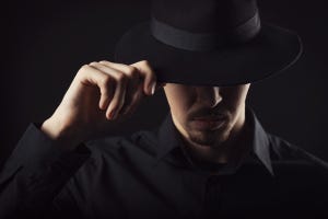 man wearing and tipping a black hat, depicting a hacker