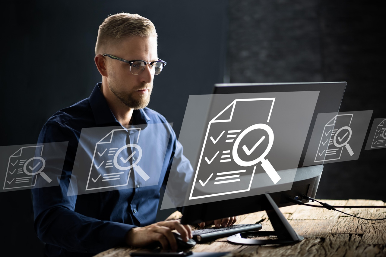 A man sitting at a computer at a desk with images of tickboxes A man sitting at a computer at a desk with images of tickboxes