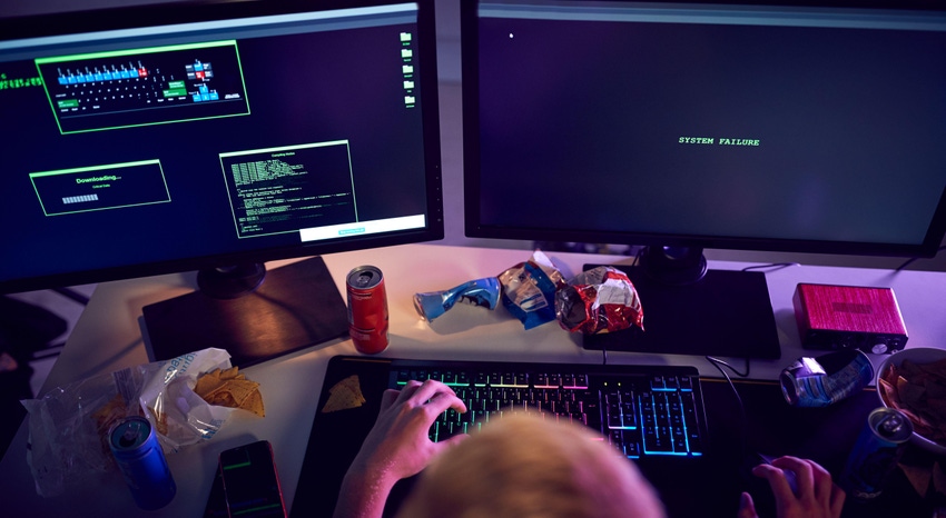 Kid sitting at computer monitors with snacks scattered around