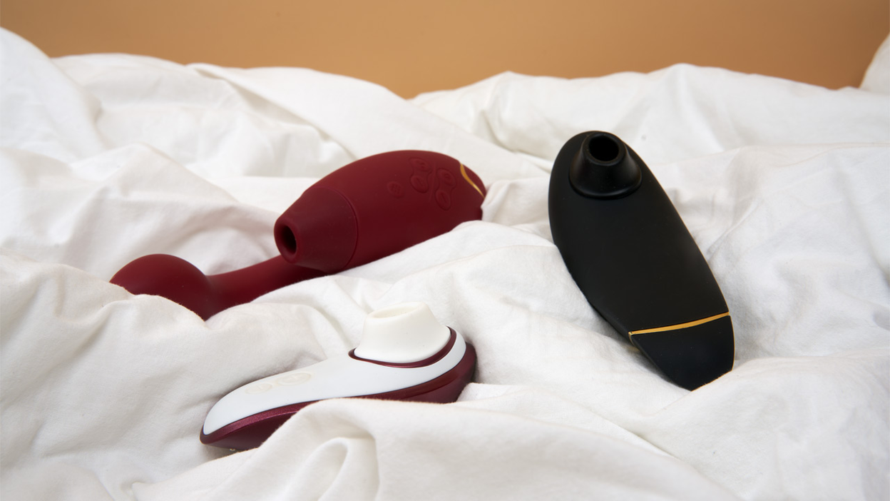 Tre produkter fra Womanizer på en seng