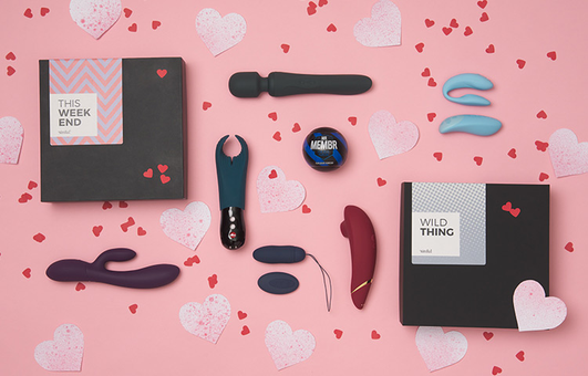 Sextoys et petits cœurs en papier posés sur fond rose