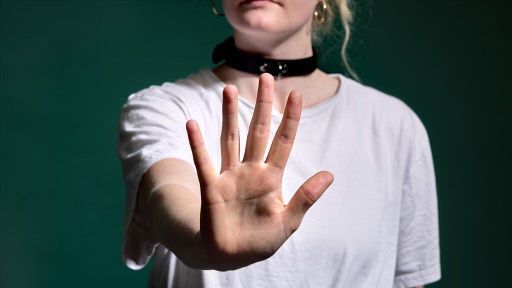 Eine Frau mit BDSM-Halsband macht ein Stoppzeichen mit ihrer Hand