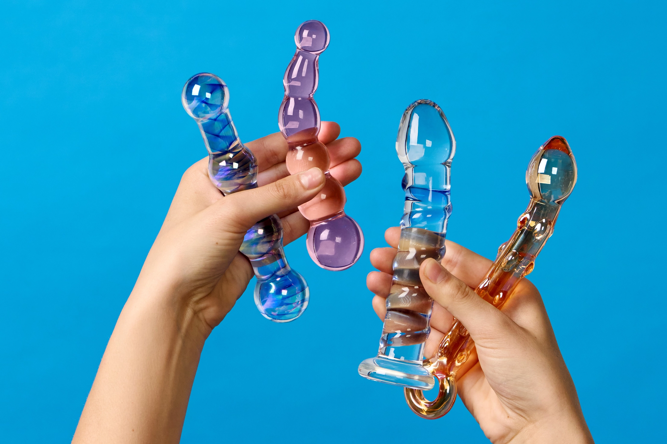 foto van handen die glazen dildo's omhoog houden