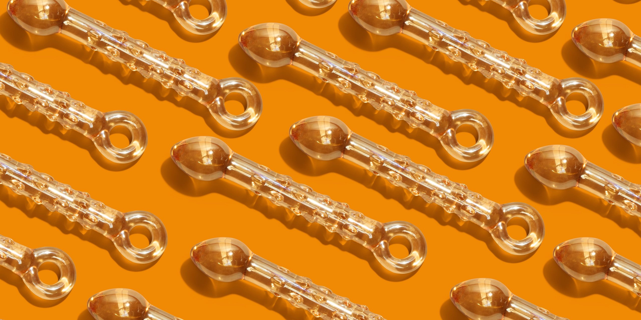 Veel glazen dildo's op een oranje achtergrond