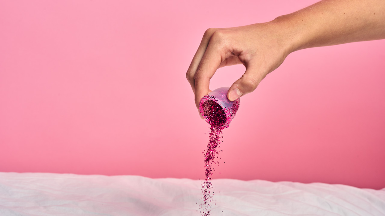 Hand pouring out glitter from a menstrual cup