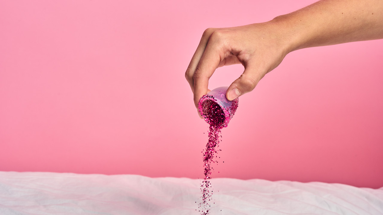 Hånd der hælder glitter ud af en menstruationskop