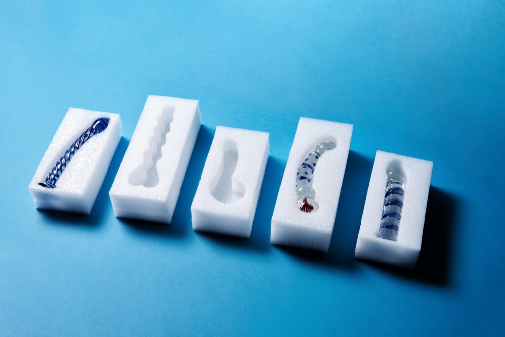 Glass dildos on foam with a blue background