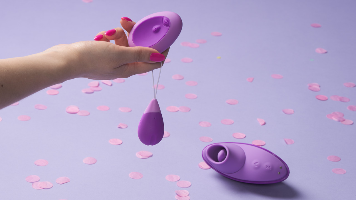 A hand holding a purple sex toy
