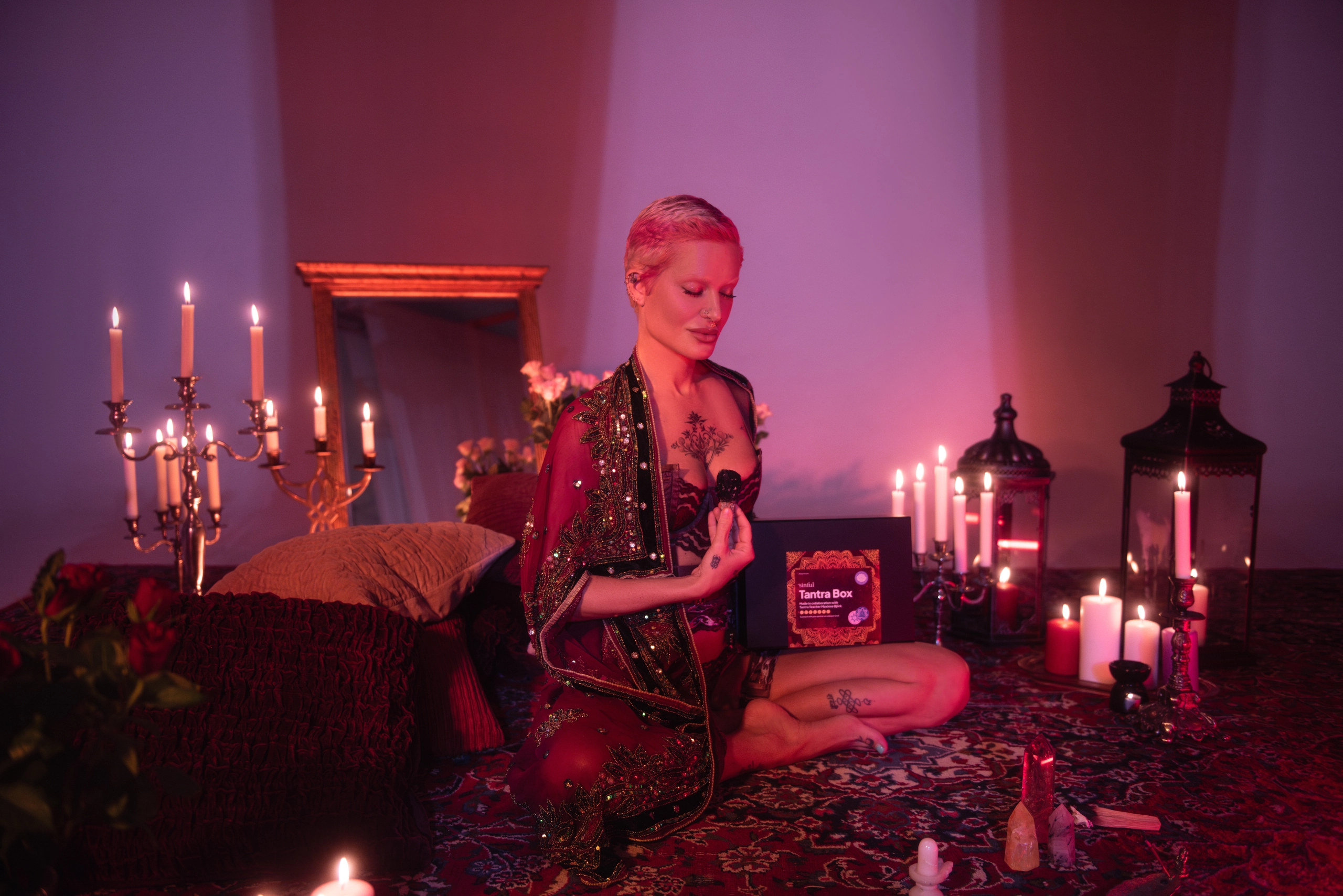 Personne assise par terre en sous-vêtements avec des bougies allumées autour d'elle.
