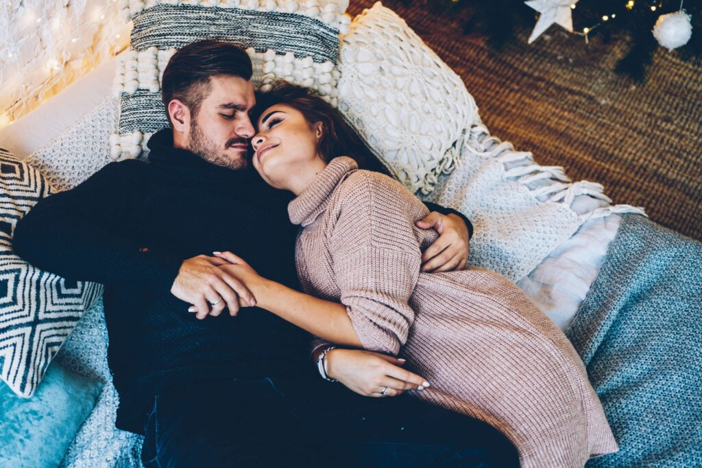 Mies ja nainen makaavat sängyssä ja pitelevät toisiaan