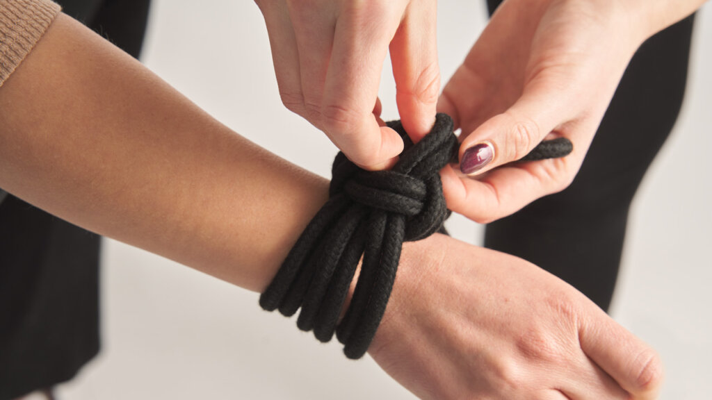 Une personne attachant les mains d'une autre personne avec une corde de bondage
