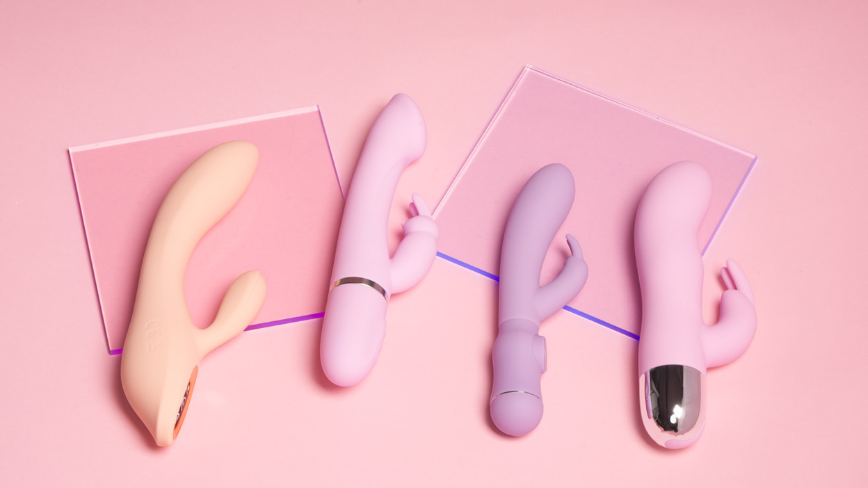 Four rabbit vibrators in bright colours lying next to each other on a pink background