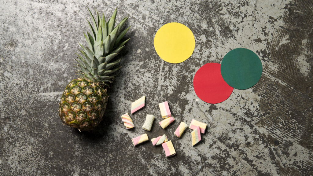 Ananas, marshmallows og tre papirbiter med forskjellige farger 