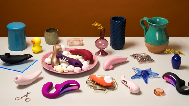 Forskjellige klitorisstimulatorer på et bord med forskjellige dekorasjoner rundt
