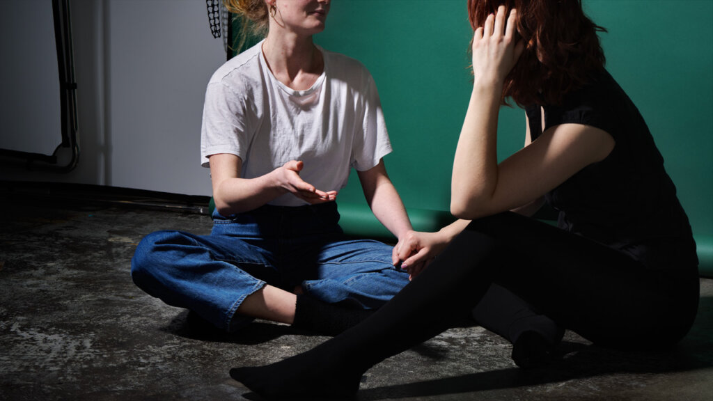 To personer der sidder på et gulv og holder i hånd