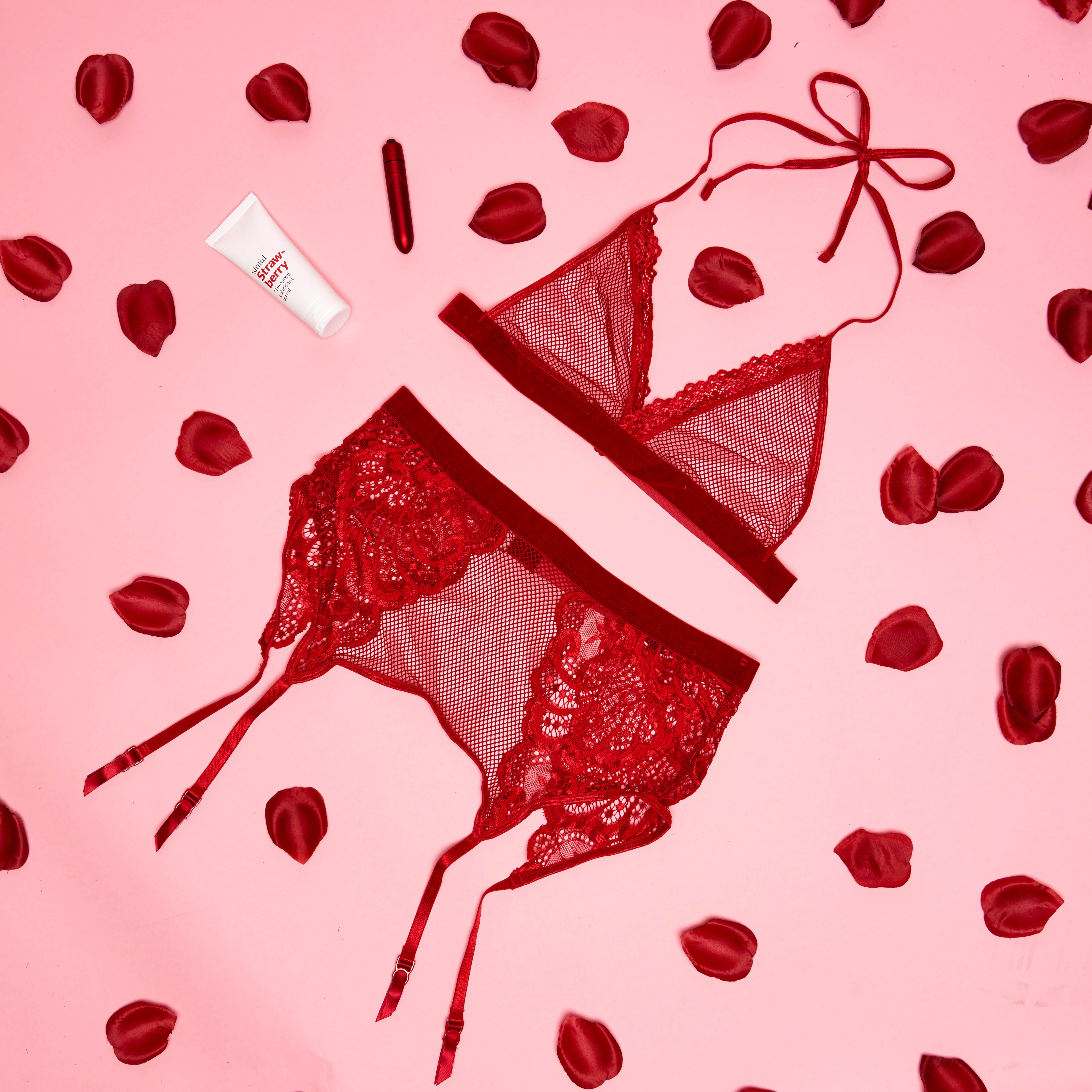 Rode lingerie met een rode vibrator en rozenblaadjes