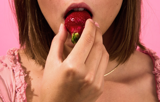 Närbild av munnen på en person som äter en jordgubbe