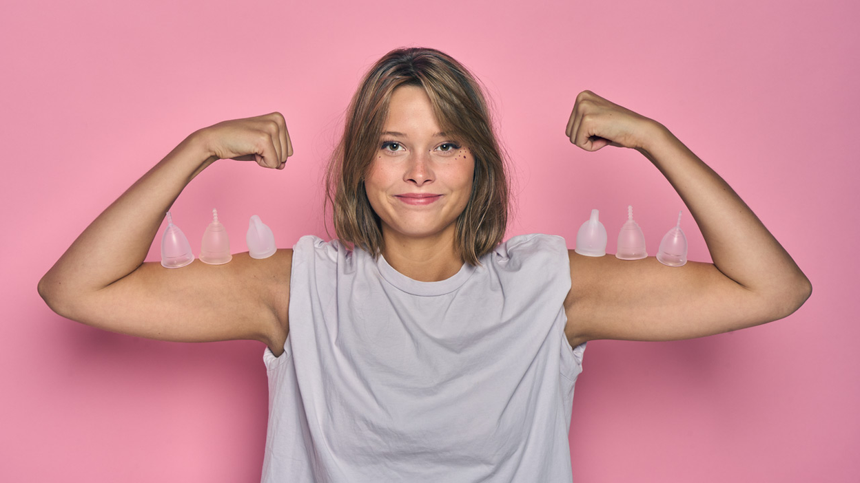 Person flexing both arms with menstrual cups on them