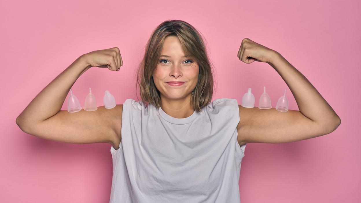 Persoon buigt beide armen met menstruatiecups op de spierballen