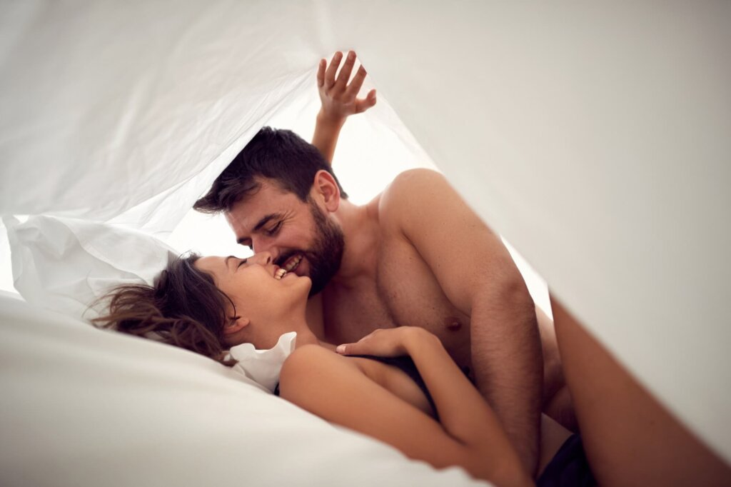 Mann und Frau liegen unter einem Laken in einem Bett