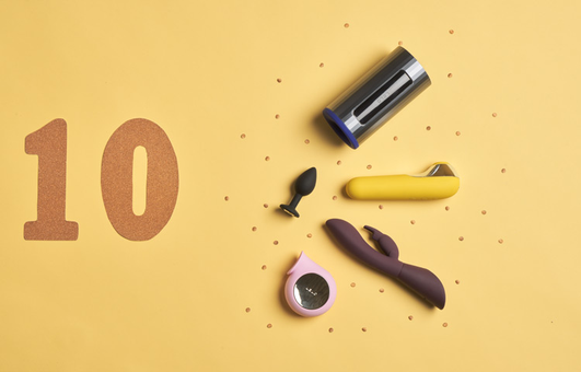 Sextoys posés sur un fond jaune avec le chiffre 10 à côté en paillettes dorées