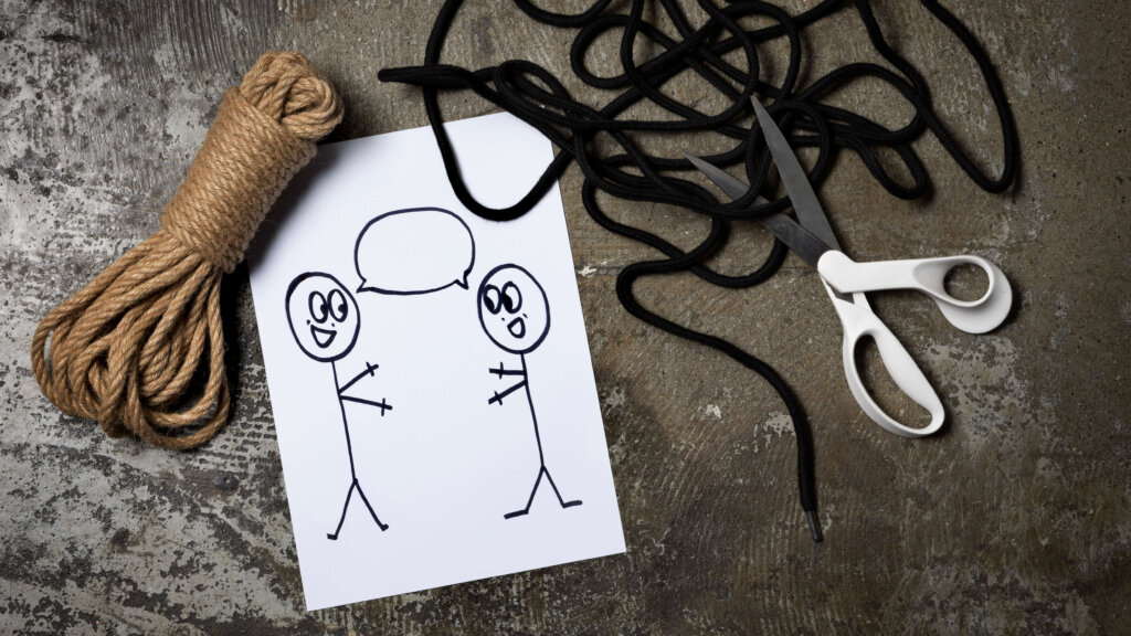 Deux cordes de bondage et des ciseaux posés à côté d'un dessin montant deux personnes discutant ensemble