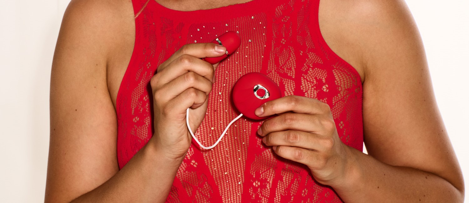 Eine Person, die in jeder Hand einen Teil desselben roten Sexspielzeugs hält.