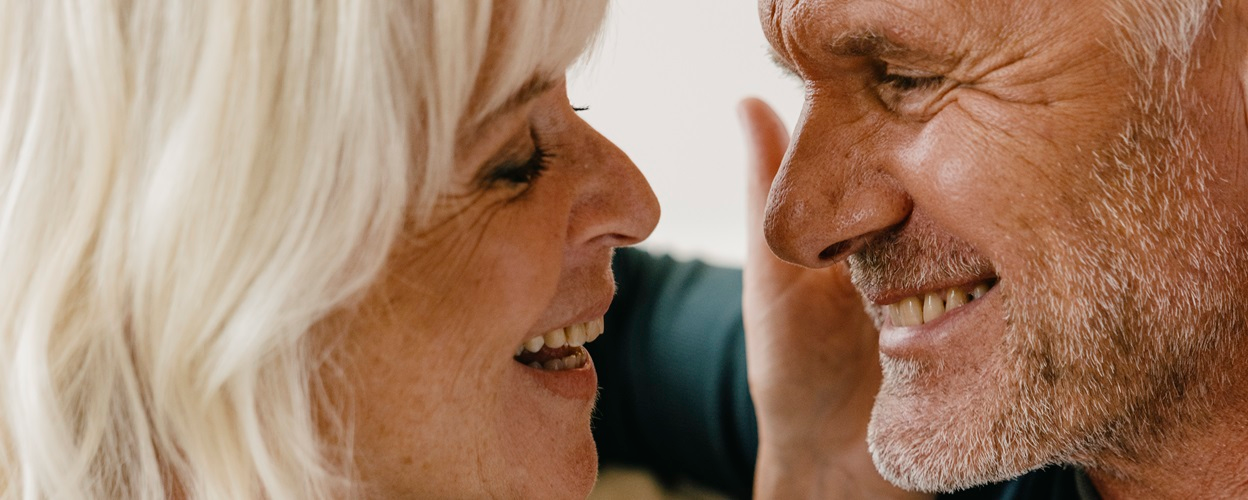 Close-up van twee oudere mensen die naar elkaar glimlachen