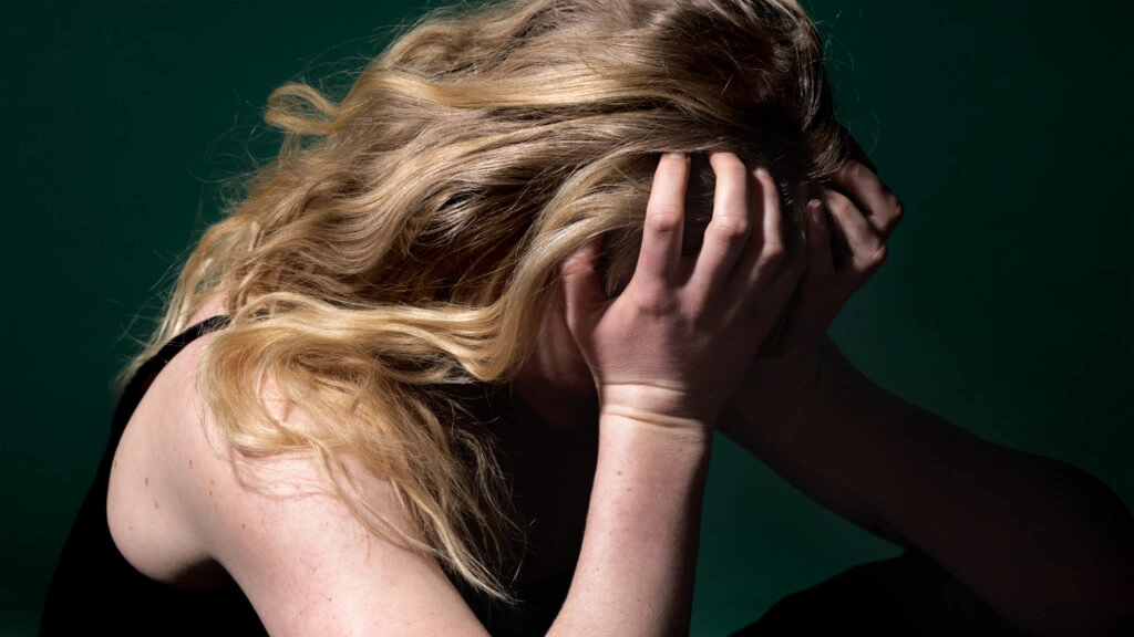 Femme assise, couvrant son visage avec ses mains