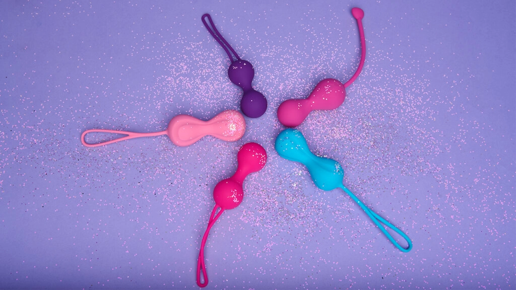 Fem vaginakuler i forskjellige farger på en lyselilla bakgrunn med glitter