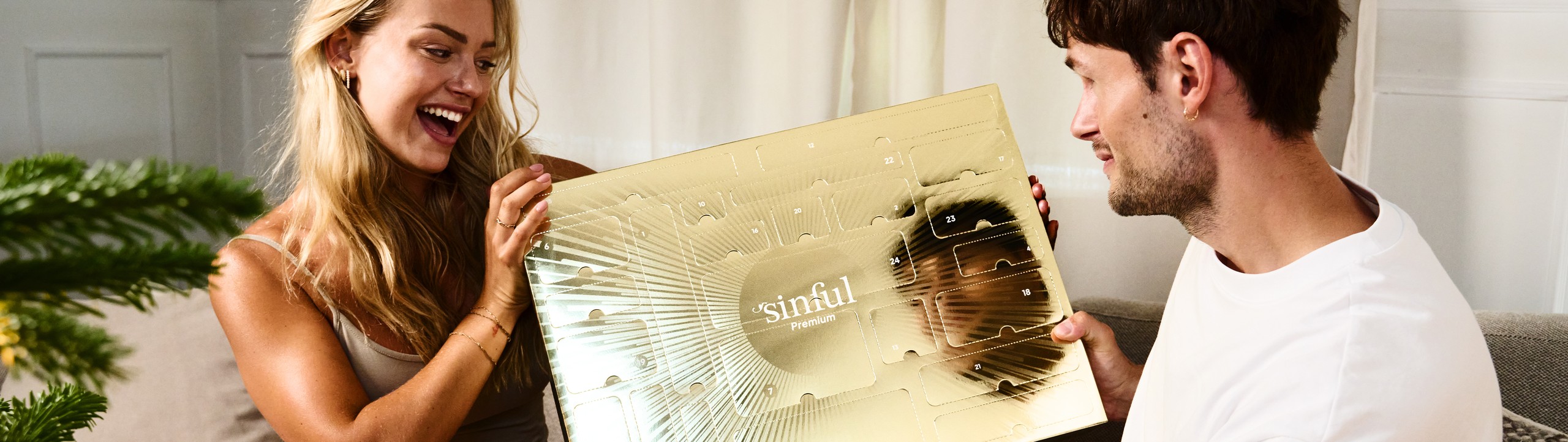 Un homme et une femme qui se regardent, avec un calendrier de l'Avent sexy Sinful entre eux