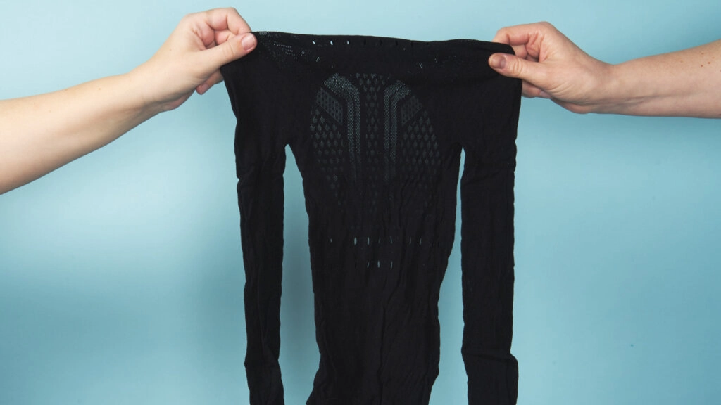 Svart bodystocking med lange ermer holdes av to hender.