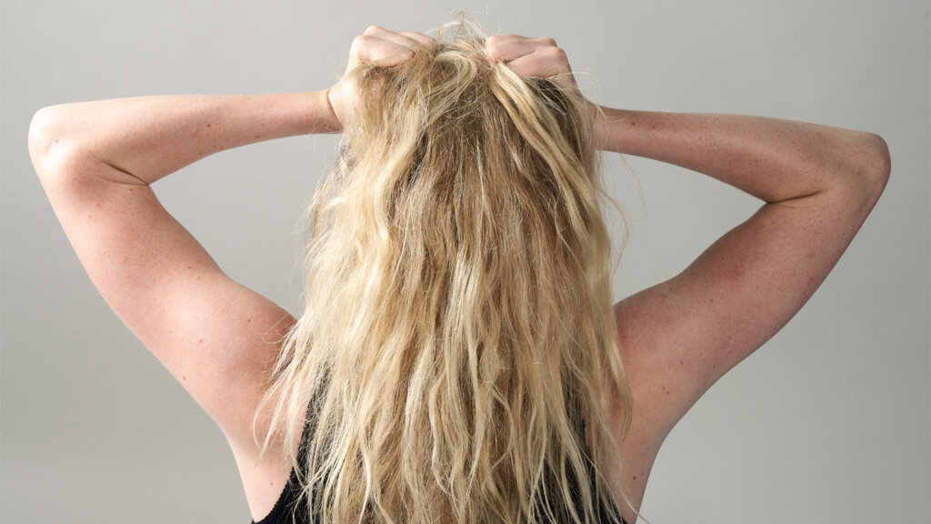 Blond person bakifrån som kramar om sitt hår i frustration