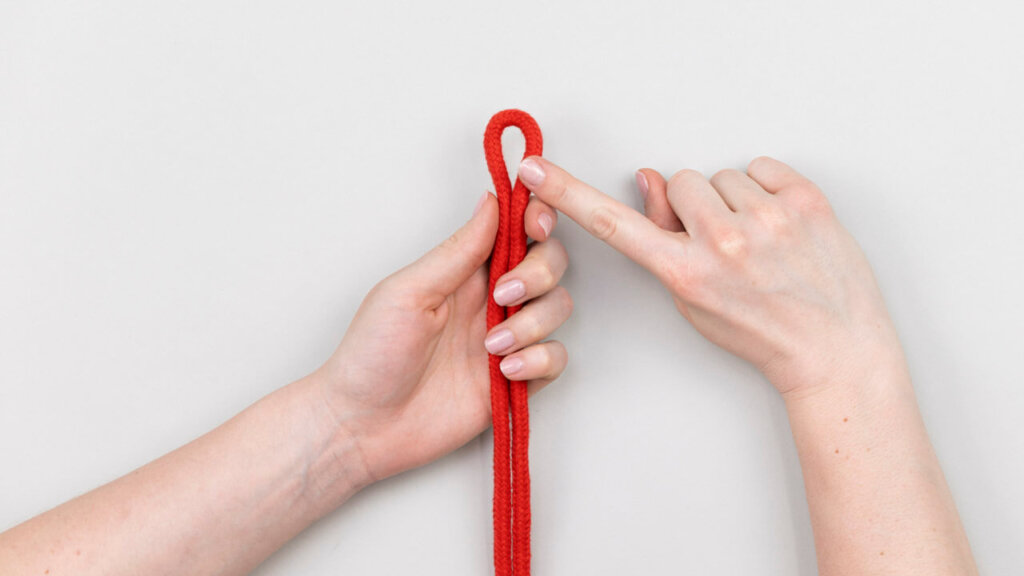 Der Finger zeigt auf eine Schlaufe aus einem Bondage-Seil
