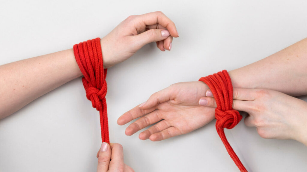 Zwei Handgelenke mit einem Bondage-Seil um sie herum