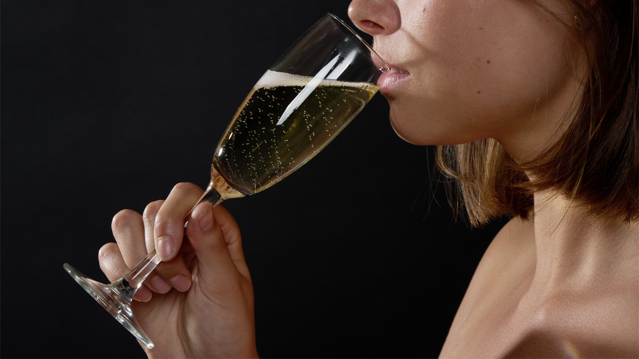 En person drikker et glass champagne