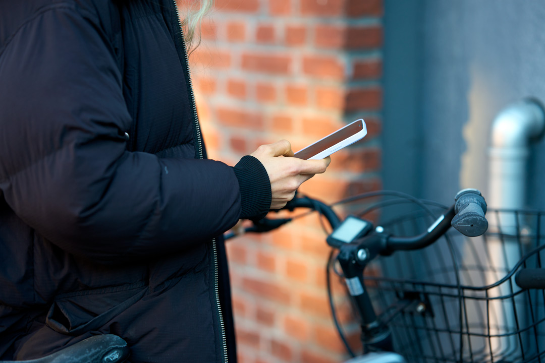 Person står bredvid en cykel med en mobil i handen
