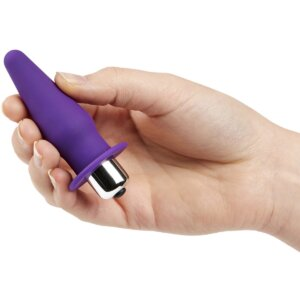 Purple butt plug with vibrator being held in a hand 