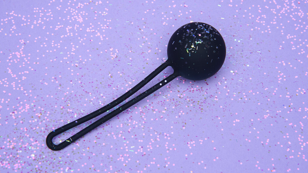 Black kegel ball on light purple background with glitter 